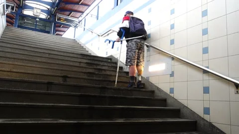 Disabled senior invalid man with leg prosthesis with crutches go up the stairs Stock Footage 159063482