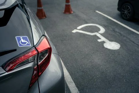 Disabled sign on back window of car and disabled parking sign on ground Stock Photos