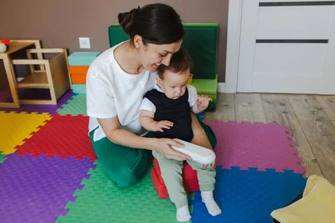Disabled toddler boy playing developmental game at private therapist office. Photos