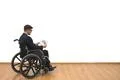 The disabled in a wheelchair holding papers on the white wall background Photo