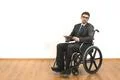 The disabled in the wheelchair holding a tablet on a white wall background Photo