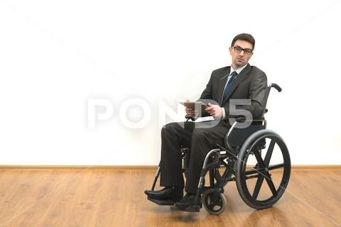 The disabled in the wheelchair holding a tablet on a white wall background Stock Photos