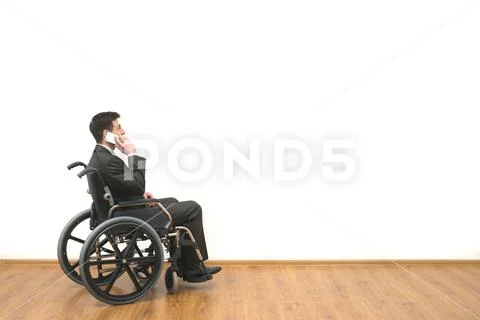 The disabled in a wheelchair phones on the white wall background Stock Photos