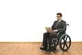The disabled in the wheelchair works with a laptop on the white wall backgrou Photo