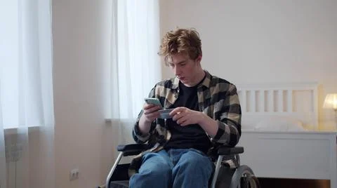 A disabled young man dials a number from a bank card Photos