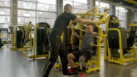 Disabled young man with instructor working out in gym Stock Footage 125531457