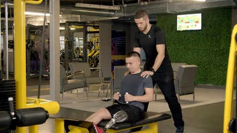 Disabled young man with instructor working out in gym Stock Footage 125533382