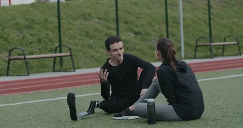 Disabled young man with prosthetic running blade talking with woman. Male Stock Footage 148484778