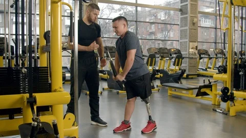 Disabled young man working out with the help of instructor in gym Stock-Footage 125532578