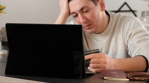 Disappointed man looking at his laptop with credit card in hand Stock Footage 263195799
