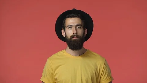 Disappointed, pissed middle-eastern bearded man in yellow t-shirt, black hat Stock Footage 115777540