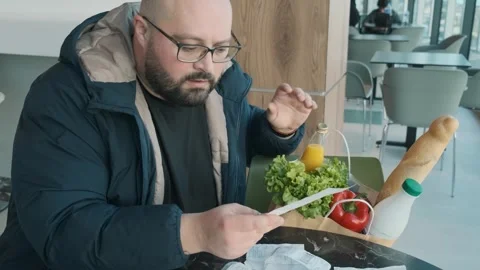 Disappointed plus size man feeling stressed while reviewing expenses with Stock Footage 285537692
