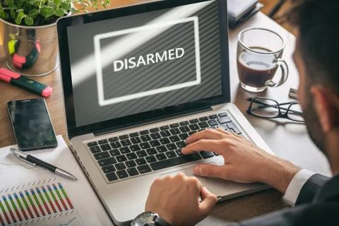 Disarmed concept. Man working with a computer, disarmed text on the screen, b Foto stock