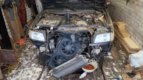 Disassembled car engine undergoing extensive repair in a messy garage Видео 337880734