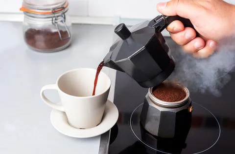 Disassembled coffee maker with one part on the fire and the other serving cof Stock Photos