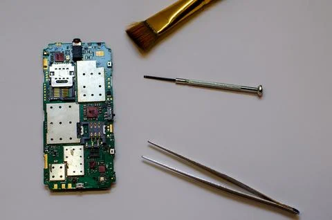 Disassembled mobile phone on the table of a mechanical engineer during repair Stock Photos
