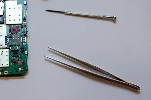 Disassembled mobile phone on the table of a mechanical engineer during repair Stock Photos