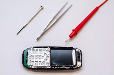 Disassembled mobile phone on the table of a mechanical engineer during repair Stock Photos