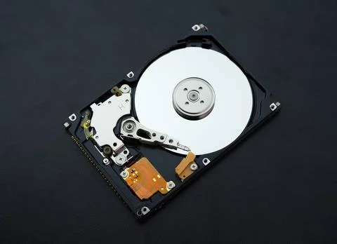 Disassembled open hard disk drive HDD of computer or laptop lies on dark ma.. Stock Photos