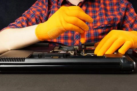 Disassembling a laptop in a workshop. the wizard unscrews the laptop cover wi Foto stock