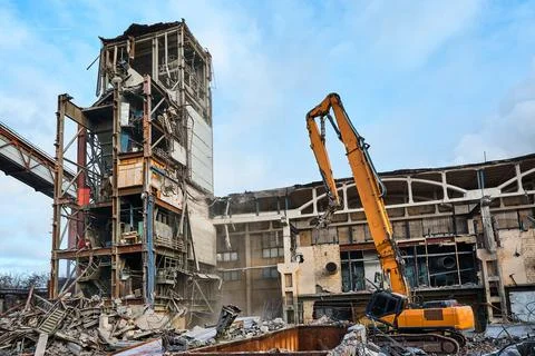 Disassembling of old industrial building by high excavator Stock Photos