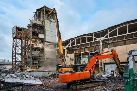 Disassembling of old industrial building by high excavator Stock Photos