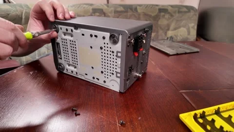 Disassembling a stereo device with a screwdriver on a wooden table Stock Footage 303505825