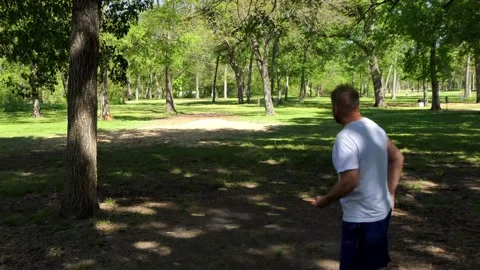 Disc golf player makes nice long drive shot that angles away from green at end Видео 156818047