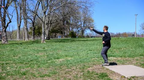 Disc golf player throwing a disc in the park. Stock Photos