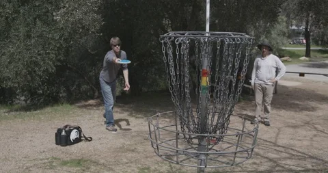 Disc golf putting into basket Stock Footage 104460567