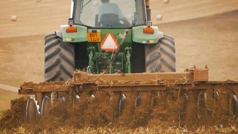 Disc harrow farming implement harrowing dry soil in slow motion Stock Footage 95392498