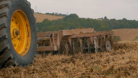 Disc harrow farming implement harrowing dry soil in slow motion Stock Footage 95392745
