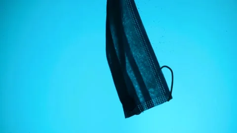 Discarded face mask slowly drifting in blue deep of water column. Coronavirus Stock Footage 154487221