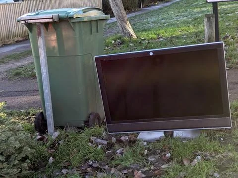 Discarded Flat Screen Television Dumped on Grass Verge Next to Public Trash B Stock Photos