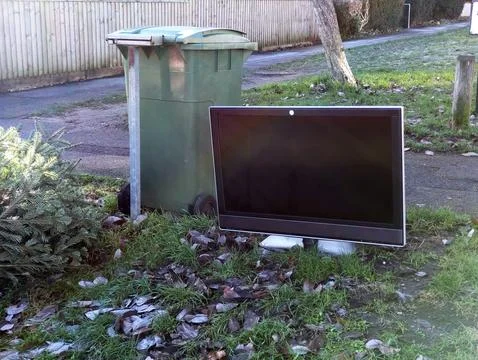 Discarded Flat Screen Television Dumped on Grass Verge Next to Public Trash B Stock Photos