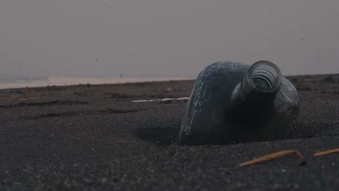 Discarded glass bottle lying on a sandy beach Vidéo 326989762