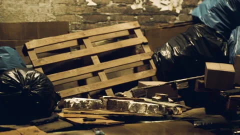 Discarded materials and bags clutter a dimly lit storage area at night Stock Footage 310501336