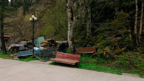 Discarded materials and old benches along a path at the base of a mossy hill in Stock-Footage 335921489