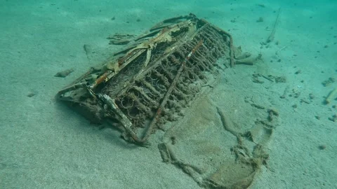 Discarded old sofa lying on sandy seabed in sun glare, Forward movement, Slow Stock Footage 255112606