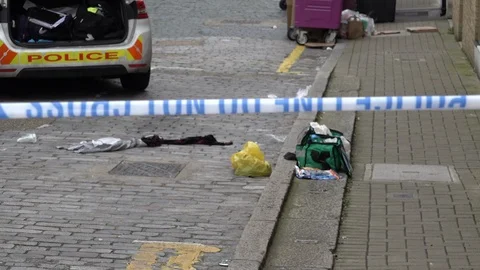 A discarded paramedic kit lies next to strewn clothing at the scene of a Stock Footage 126772178