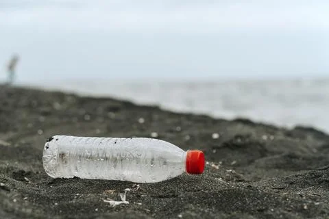 Discarded plastic bottle on a dark sand beach Fotos de archivo