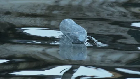 Discarded plastic bottle floating on polluted oily water surface Stock Footage 345740867