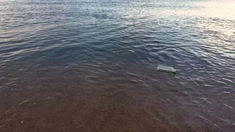 Discarded plastic bottle floating in the sea near the shoreline. Marine Stock Footage 337412014