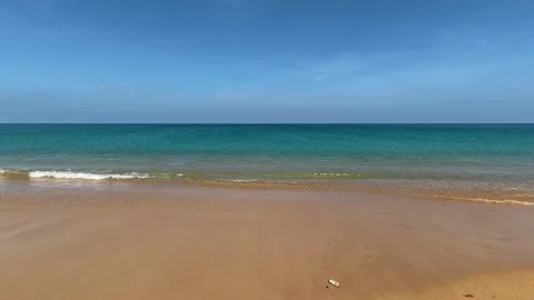 A discarded plastic bottle rolling along the shore with the waves in the Видео 345112415