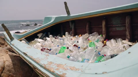Discarded plastic bottles fill abandoned boat on sandy beach, environmental Stock Footage 263954089