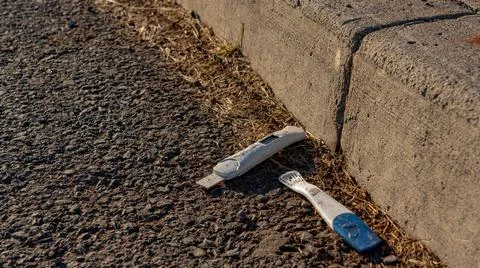 Discarded pregnancy test strip by the side of the road Stock Photos