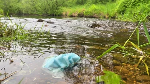 A discarded single-use mask in a river Stock Footage 155172310