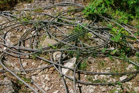 Discarded wire cables tangled on the ground in a natural outdoor setting Stock Photos
