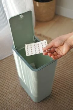 Discarding medication in a green trash bin Stock Photos