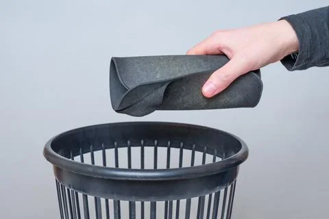 Discarding a Rolled Worn Mouse Pad into a Trash Bin 스톡 사진